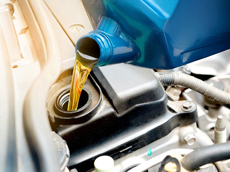 Dublin Buick GMC in Dublin CA technician pouring oil into engine